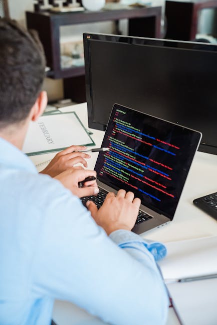 Close-up photograph of a computer screen displaying lines of colorful HTML and CSS coding text against a dark background. The code includes tags such as <h1>, <div>, <img>, and class attributes with v